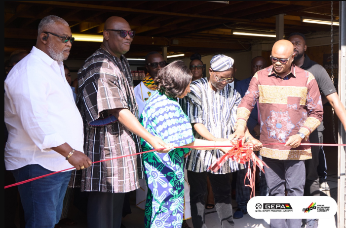 Mr Arthur (fourth from left) being assisted by Mr Dogbe (right) and Ms Benson (middle) to cut the tape to open the Trade House. With them is Mr Madjie (second from left)