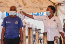 • A Ugandan health worker checks a patient's temperature at a temporary health clinic