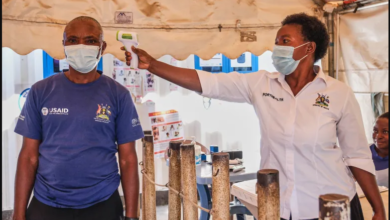 • A Ugandan health worker checks a patient's temperature at a temporary health clinic