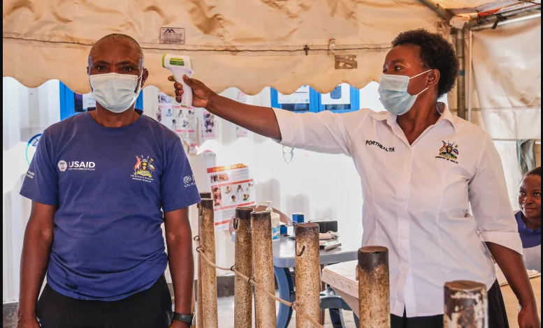 • A Ugandan health worker checks a patient's temperature at a temporary health clinic