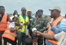 Mr Omani-Mensah (wearing a yellow reflector and standing second from left), briefing Mr Ayariga (right)