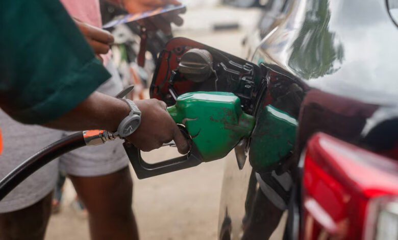 A customer stands near an attendant filling up his car at a filling station, as fuel costs rise in Abuja, Nigeria