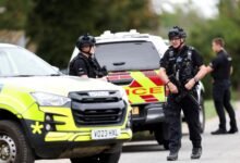 Armed police officers work on a road outside the perimeter of the RAF Fairford airbase, after police declared a major incident at the base