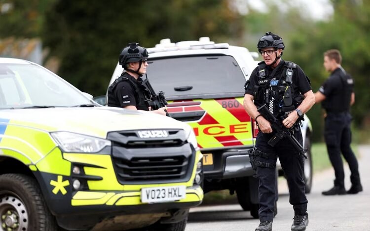 Armed police officers work on a road outside the perimeter of the RAF Fairford airbase, after police declared a major incident at the base