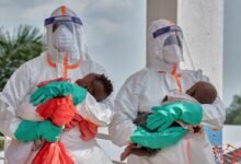 Congolese medical workers dressed in personal protective equipment (PPE) carry children tested and cleared off from Ebola