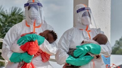 Congolese medical workers dressed in personal protective equipment (PPE) carry children tested and cleared off from Ebola