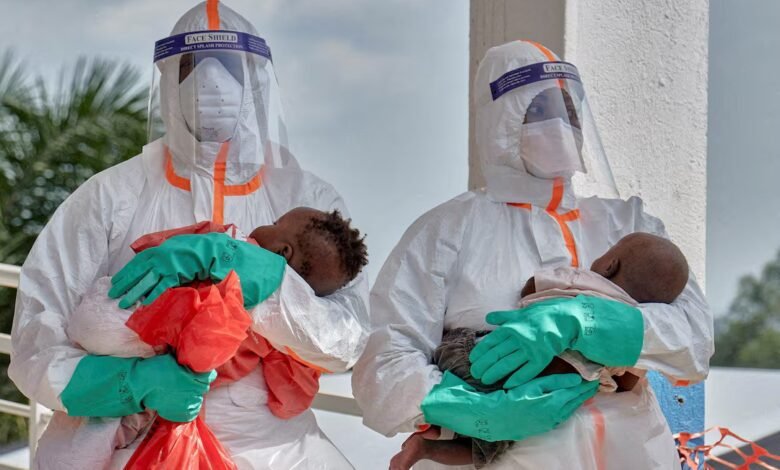 Congolese medical workers dressed in personal protective equipment (PPE) carry children tested and cleared off from Ebola