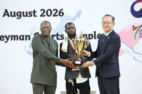 Mr Lartey Otu (left) and Mr Kyongsig presenting a trophy to a coach of the Greater Accra team