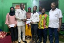 Alhaji Ibrahim (second from left) presenting the cash to a beneficiary