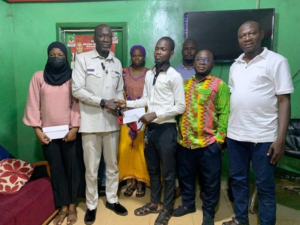 Alhaji Ibrahim (second from left) presenting the cash to a beneficiary