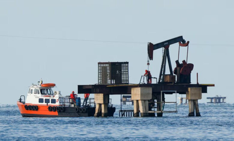 Workers of Venezuelan state oil company PDVSA labour at an operating pumpjack in Lake Maracaibo, in Cabimas, Venezuela