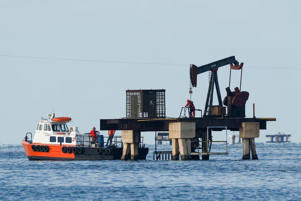 Workers of Venezuelan state oil company PDVSA labour at an operating pumpjack in Lake Maracaibo, in Cabimas, Venezuela
