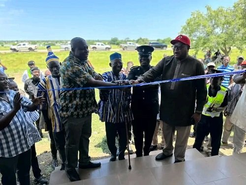 (in set) Mr Kuuire (in cap) being assisted by ASP Banafo and Mr Ziniel (second from left) to cut the tape to open the Police Post at Kokoligu