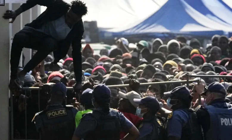 A Malawian migrant jumps over a barricade as the police officer manage the queue for their deportation at a temporary centre, in Durban