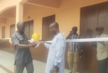 Mr Nkrunah (left) being assisted by a guest to cut the tape to open the newly constructed school building at Bonniekope