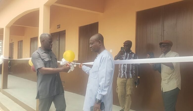 Mr Nkrunah (left) being assisted by a guest to cut the tape to open the newly constructed school building at Bonniekope