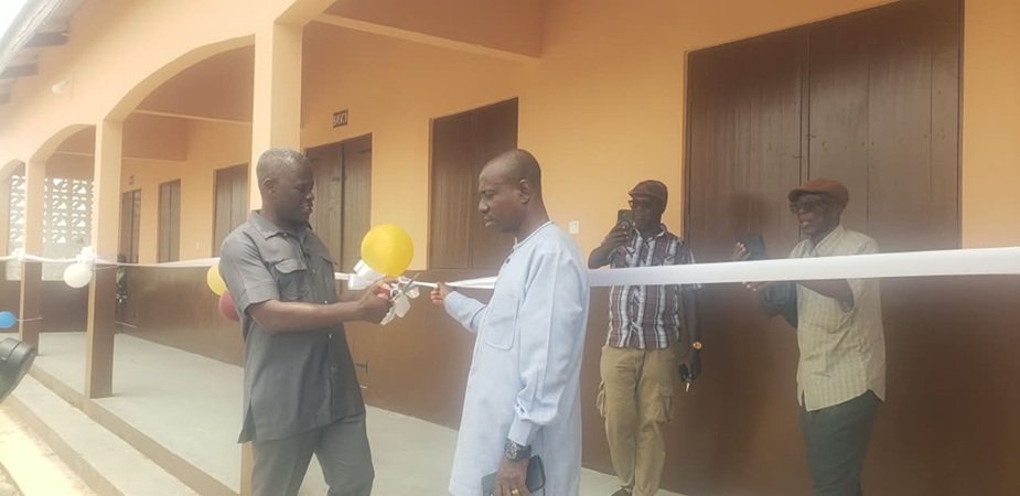 Mr Nkrunah (left) being assisted by a guest to cut the tape to open the newly constructed school building at Bonniekope