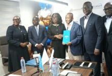Mr Ofori-Poku (third from right) exchanging the signed document with Mrs Osei-Poku, while officials of the two organisations look on