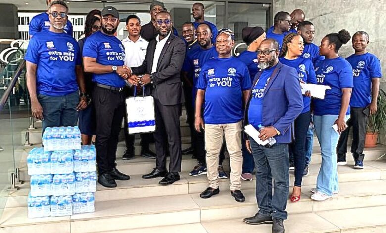 Mr. Appiah Otoo (second from left) presenting the water to Mr. Delali Gaisi (third from right, front row)