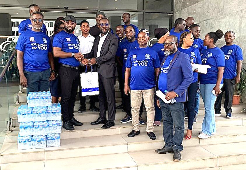 Mr. Appiah Otoo (second from left) presenting the water to Mr. Delali Gaisi (third from right, front row)