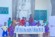 Mr Kpormegbey (right, back row) presenting the packed meals to the children