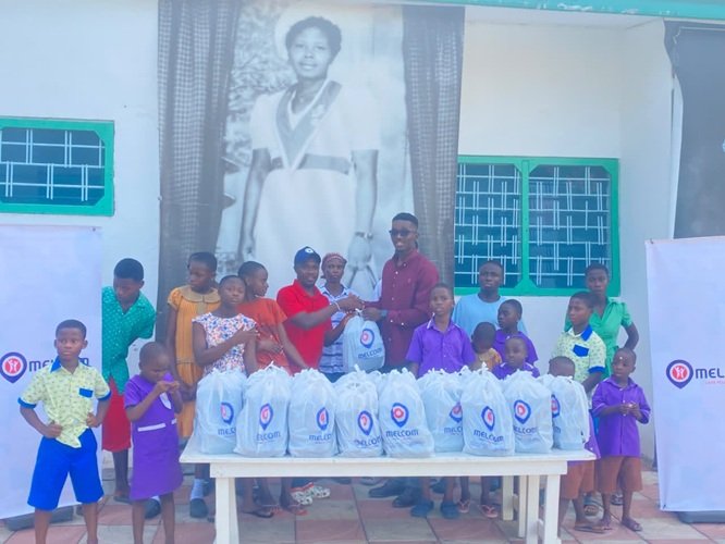 Mr Kpormegbey (right, back row) presenting the packed meals to the children