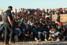 Migrants and asylum seekers wait in line to receive food and drink from the Red Cross in Ceut, Spain