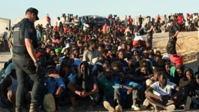Migrants and asylum seekers wait in line to receive food and drink from the Red Cross in Ceut, Spain