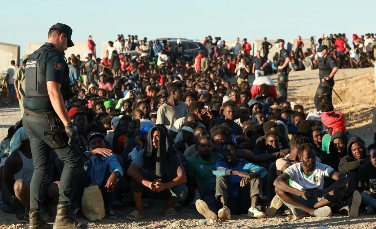 Migrants and asylum seekers wait in line to receive food and drink from the Red Cross in Ceut, Spain