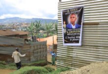People walk past a banner of Marie-Celestin Karondwa