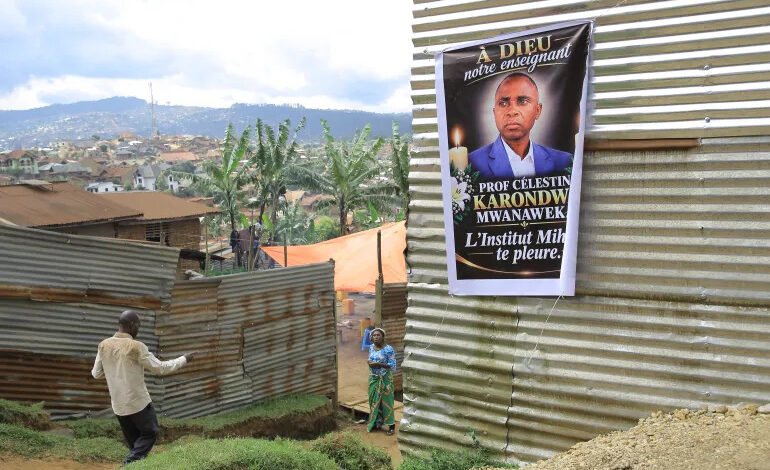 People walk past a banner of Marie-Celestin Karondwa