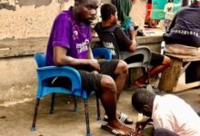 A traditional nail cutter attending to a client at a trotro station
