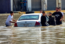 People gather by a vehicle along a flooded street following heavy rains in Libya's capital Tripoli