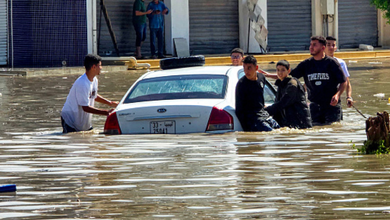 People gather by a vehicle along a flooded street following heavy rains in Libya's capital Tripoli