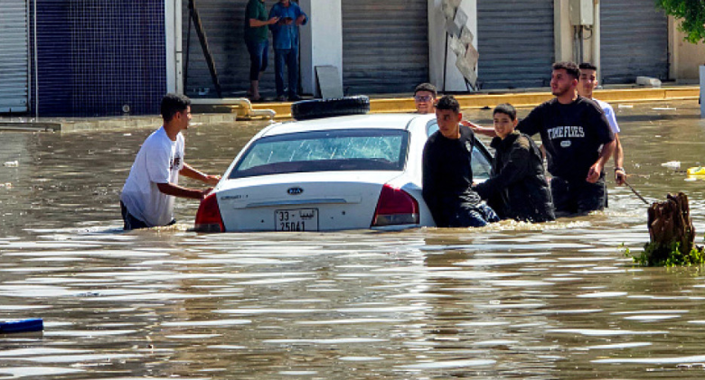 People gather by a vehicle along a flooded street following heavy rains in Libya's capital Tripoli