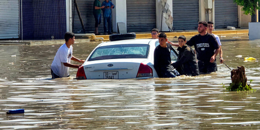 People gather by a vehicle along a flooded street following heavy rains in Libya's capital Tripoli